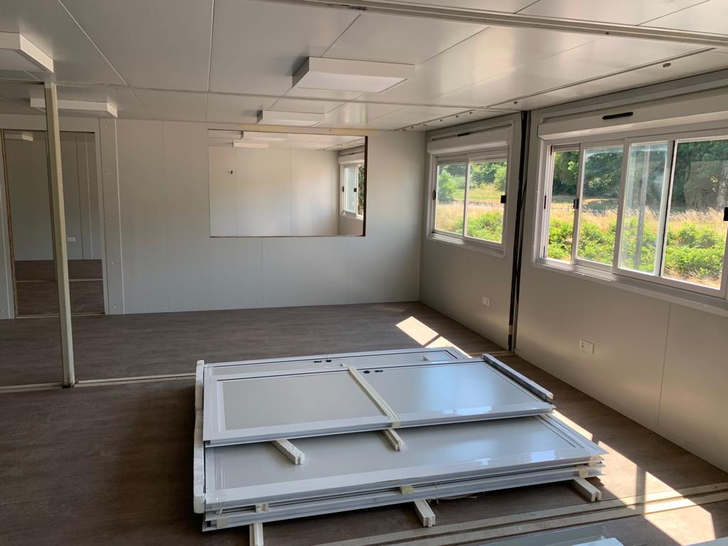 Intérieur d'un module en cours d'aménagement, cloisons et menuiseries déposées sur palette, prêtes à être réinstallées